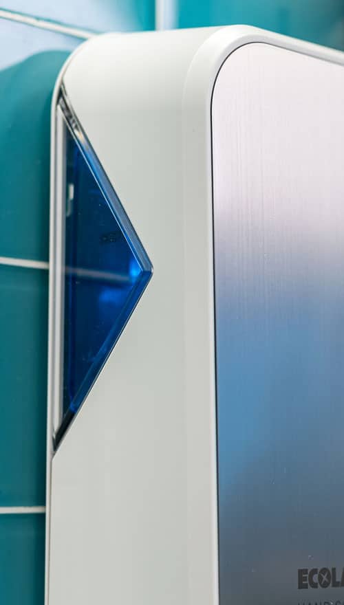 Side view of a white and blue Ecolab soap or sanitizer dispenser showing the product level.